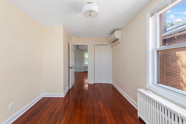 corridor featuring a wall unit AC, radiator heating unit, and dark wood-type flooring