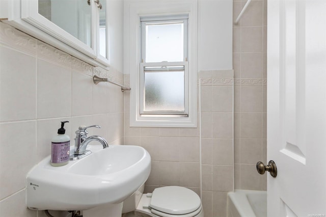 bathroom featuring toilet, sink, and tile walls