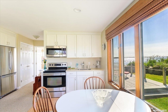 kitchen with white cabinets, light colored carpet, sink, and appliances with stainless steel finishes