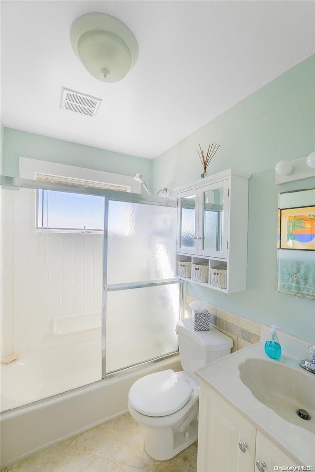 full bathroom featuring tile patterned floors, vanity, enclosed tub / shower combo, and toilet