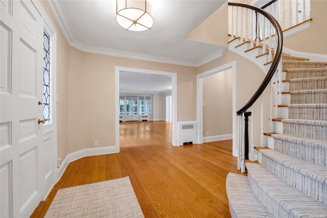 entrance foyer featuring radiator, light hardwood / wood-style flooring, and ornamental molding