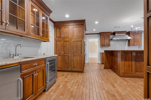 kitchen with light stone countertops, sink, wine cooler, range hood, and crown molding