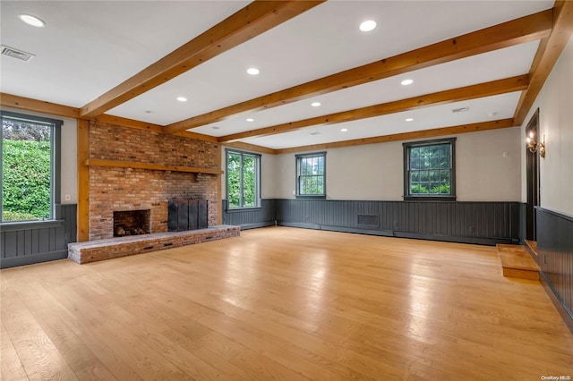 unfurnished living room with beam ceiling, light hardwood / wood-style floors, and a brick fireplace