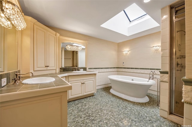 bathroom featuring vanity, tile walls, independent shower and bath, and a skylight