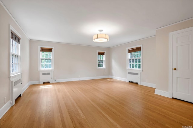 unfurnished room featuring radiator, crown molding, a healthy amount of sunlight, and light wood-type flooring