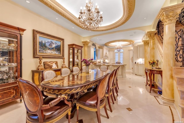 dining area with ornamental molding, decorative columns, a raised ceiling, and a notable chandelier