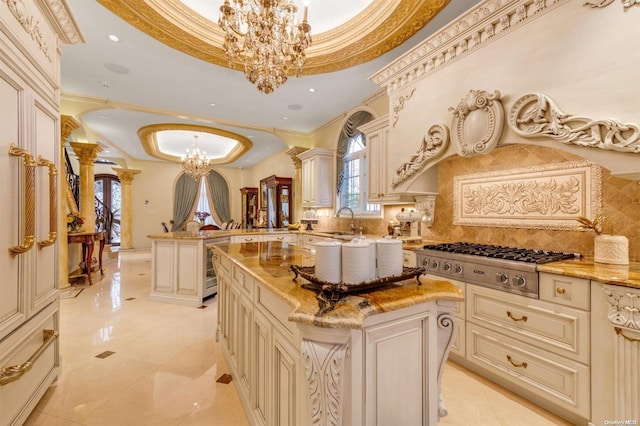 kitchen with cream cabinetry, a kitchen island, stainless steel gas cooktop, and hanging light fixtures