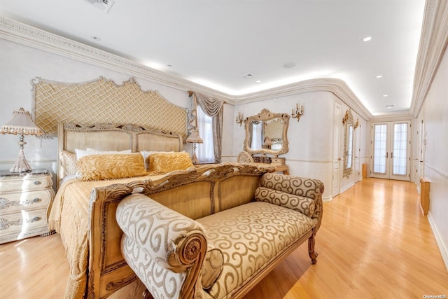 bedroom with crown molding, french doors, and light wood-type flooring