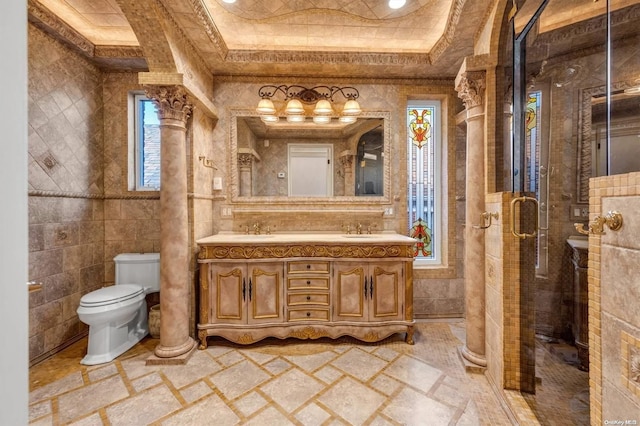 bathroom featuring decorative columns, vanity, a raised ceiling, a shower with door, and toilet