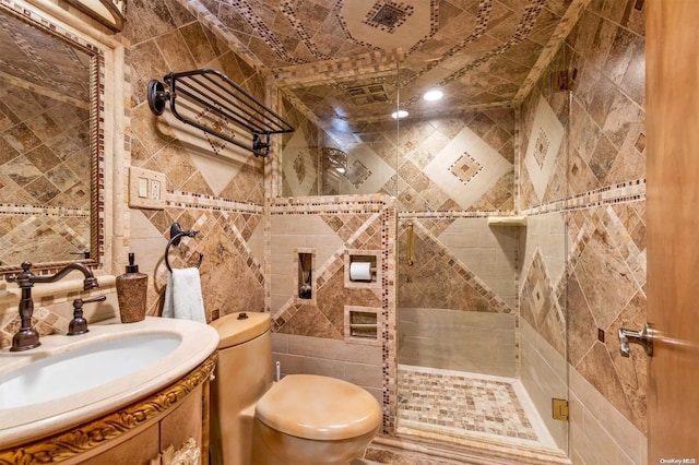 bathroom featuring walk in shower, vanity, tile walls, and toilet