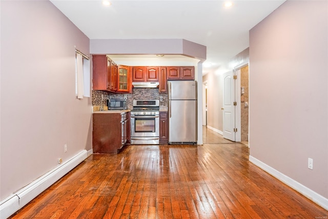 kitchen with stainless steel appliances, dark hardwood / wood-style flooring, backsplash, and a baseboard radiator