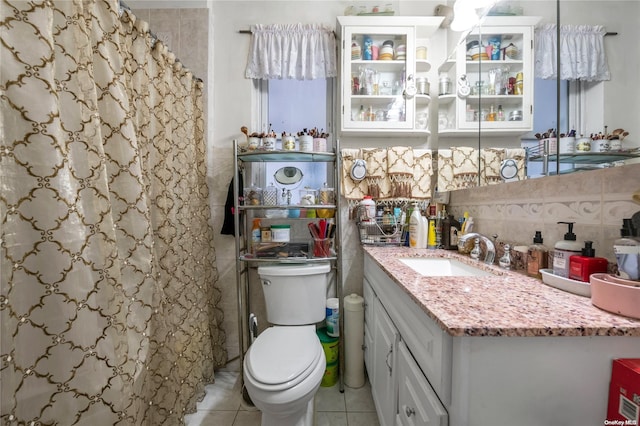 bathroom featuring walk in shower, tile patterned flooring, toilet, vanity, and tile walls