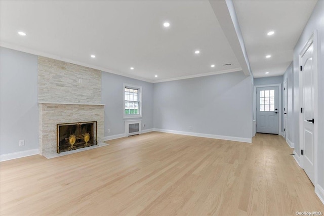 unfurnished living room featuring a fireplace, ornamental molding, light wood-type flooring, and a healthy amount of sunlight