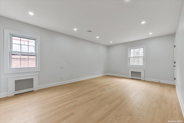 unfurnished room featuring radiator heating unit, a healthy amount of sunlight, and light hardwood / wood-style floors