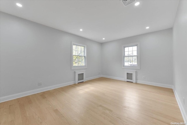 unfurnished room with radiator, light wood-type flooring, and a wealth of natural light