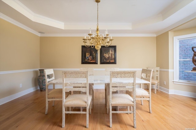 dining room with hardwood / wood-style flooring, ornamental molding, and a tray ceiling