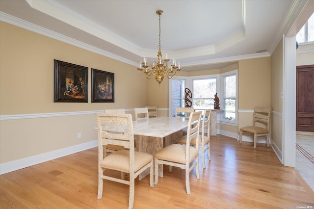 dining area with a raised ceiling, plenty of natural light, ornamental molding, and light wood-type flooring