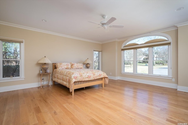 bedroom featuring multiple windows, ceiling fan, crown molding, and light wood-type flooring