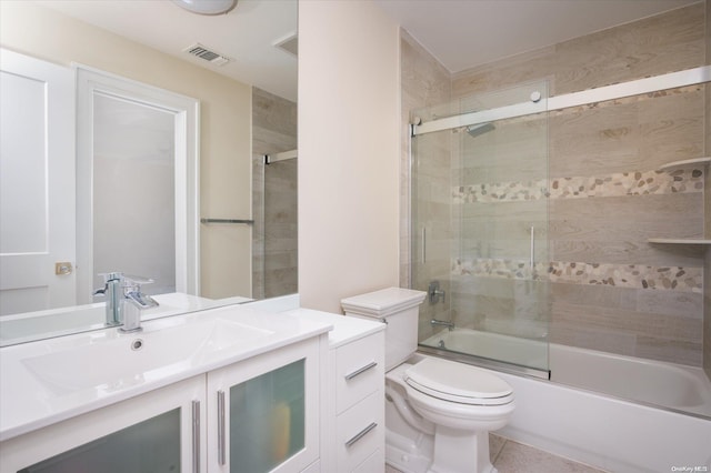 full bathroom with tile patterned floors, vanity, bath / shower combo with glass door, and toilet