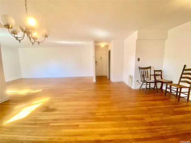 unfurnished room featuring a notable chandelier and wood-type flooring