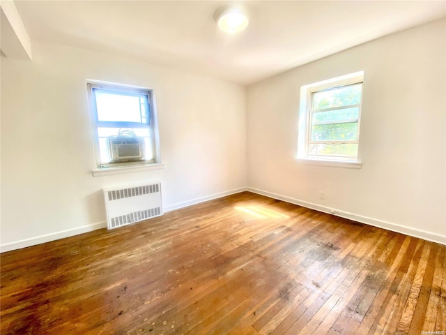 interior space with hardwood / wood-style floors, radiator heating unit, cooling unit, and a healthy amount of sunlight