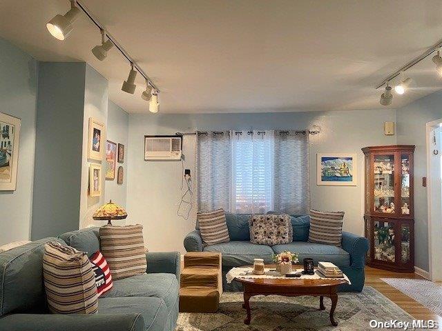 living room featuring hardwood / wood-style floors, a wall mounted air conditioner, and track lighting