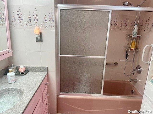 bathroom with vanity and enclosed tub / shower combo