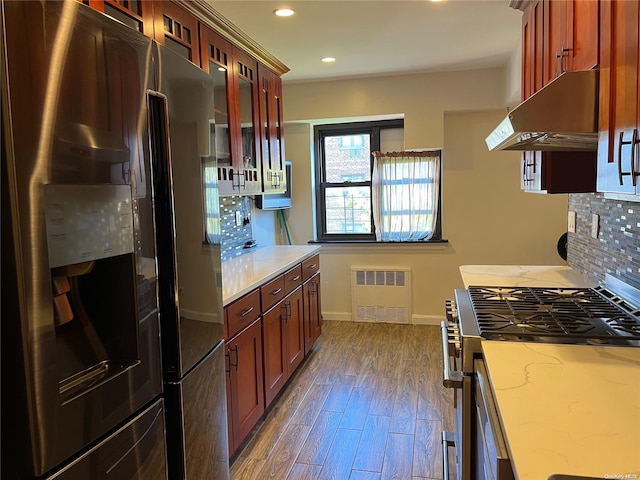 kitchen with dark hardwood / wood-style flooring, tasteful backsplash, stainless steel appliances, radiator heating unit, and range hood