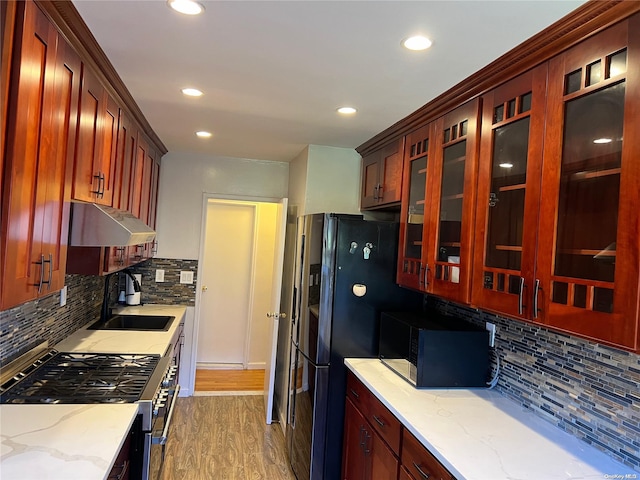 kitchen featuring light stone countertops, sink, dark wood-type flooring, backsplash, and appliances with stainless steel finishes