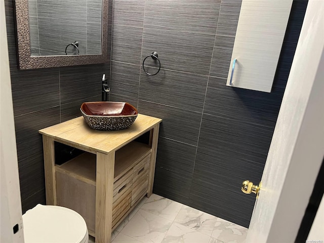 bathroom with vanity, toilet, and tile walls