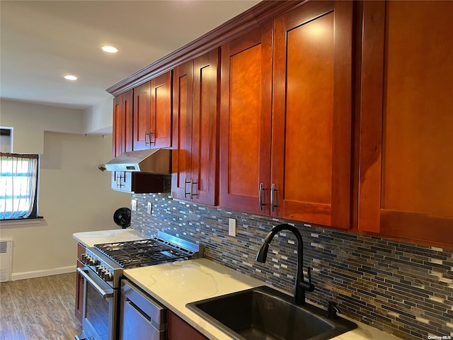 kitchen with light stone countertops, appliances with stainless steel finishes, backsplash, dark hardwood / wood-style flooring, and sink