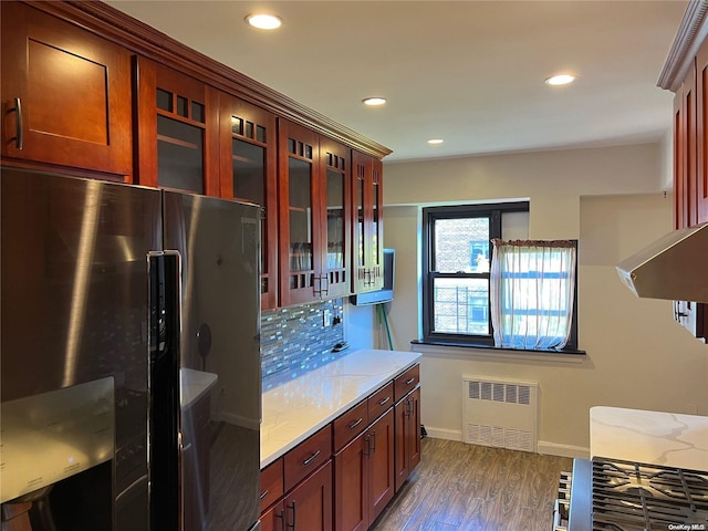 kitchen with stainless steel refrigerator, light stone countertops, radiator, dark wood-type flooring, and backsplash