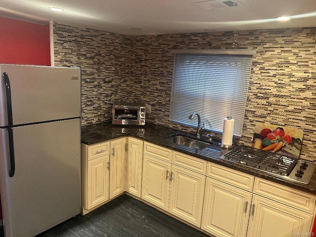 kitchen featuring sink, gas stovetop, tasteful backsplash, stainless steel fridge, and cream cabinets