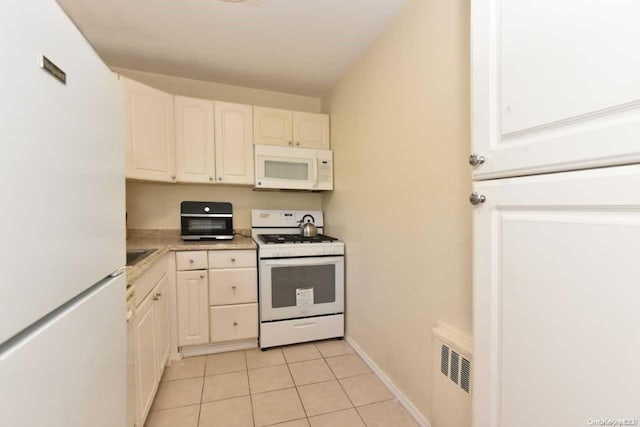 kitchen with white cabinets, white appliances, radiator heating unit, and light tile patterned floors