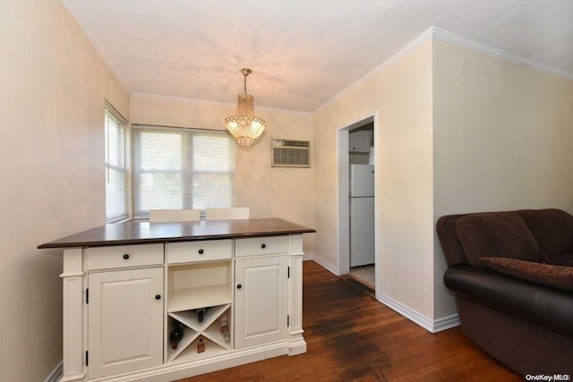 kitchen with a wall unit AC, dark wood-type flooring, crown molding, white cabinets, and hanging light fixtures