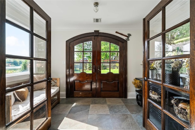 foyer featuring french doors, a wealth of natural light, and ornamental molding