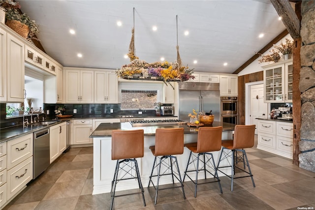 kitchen featuring appliances with stainless steel finishes, a kitchen breakfast bar, sink, a kitchen island, and lofted ceiling