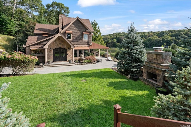 exterior space featuring a lawn, a fireplace, a patio, and french doors