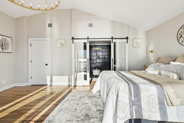 8 Shoal Dr, West Islip, NY 11795 - bedroom with a barn door, wood finished floors, high vaulted ceiling, and a chandelier