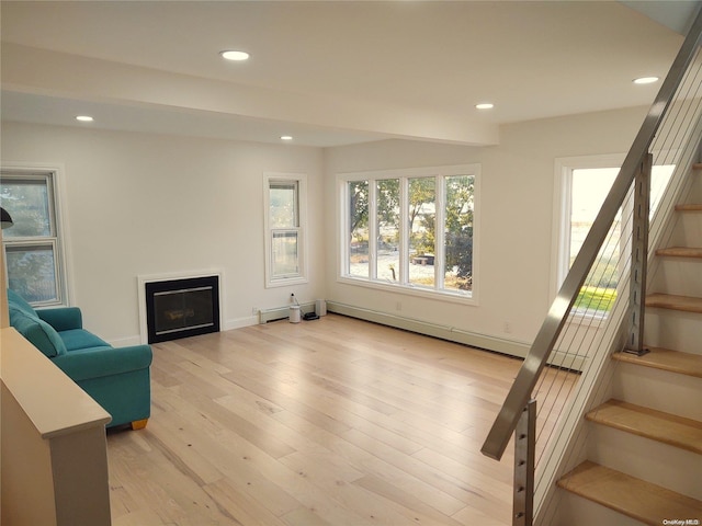 living area with a wealth of natural light, a baseboard heating unit, and light wood-type flooring