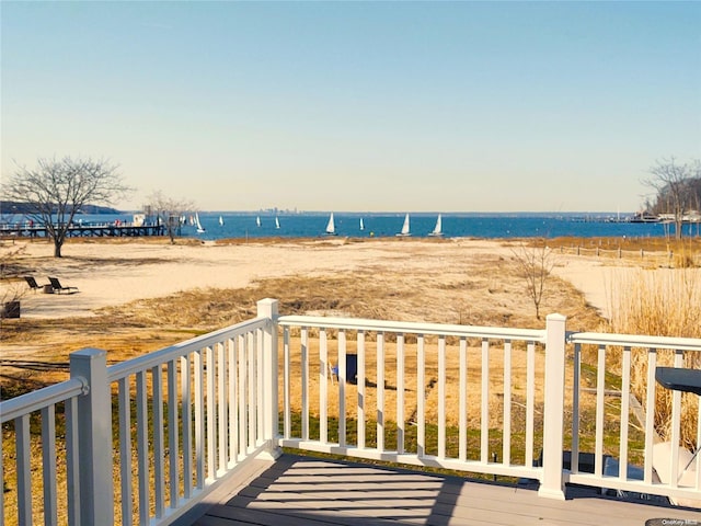 wooden terrace with a water view and a view of the beach