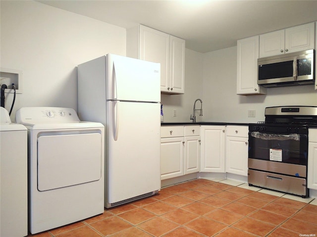 kitchen with light tile patterned floors, white cabinetry, washing machine and clothes dryer, appliances with stainless steel finishes, and sink