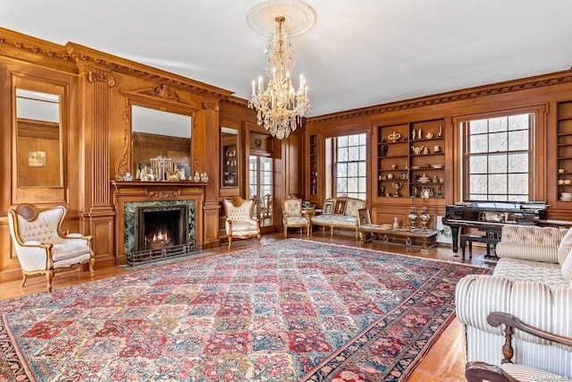 sitting room featuring an inviting chandelier, built in features, a wealth of natural light, and wooden walls