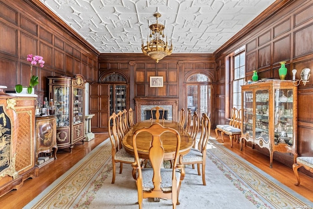 dining area with wood walls, crown molding, wood-type flooring, and a textured ceiling