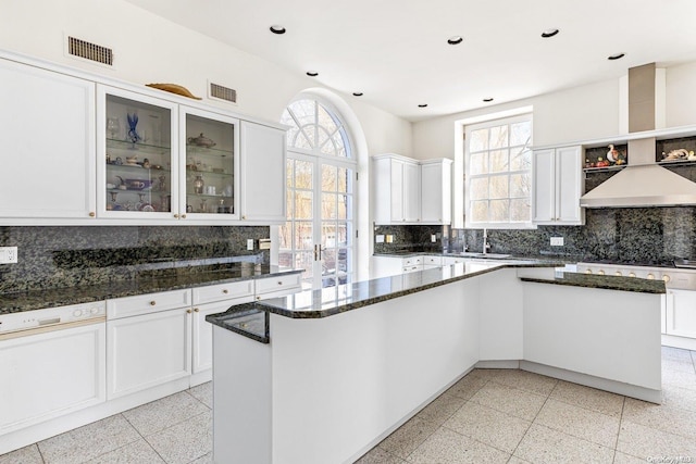 kitchen featuring a center island, backsplash, dark stone counters, white cabinets, and sink