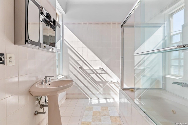 bathroom featuring tile patterned floors, bath / shower combo with glass door, and tile walls