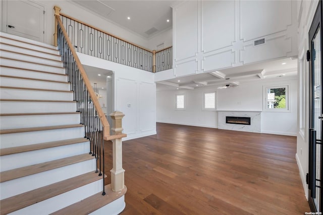 unfurnished living room with a towering ceiling, a high end fireplace, and hardwood / wood-style flooring