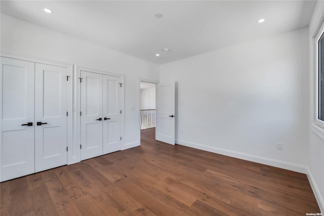 unfurnished bedroom featuring dark wood-type flooring and multiple closets