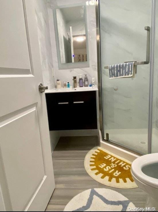 bathroom with hardwood / wood-style flooring, vanity, toilet, and walk in shower