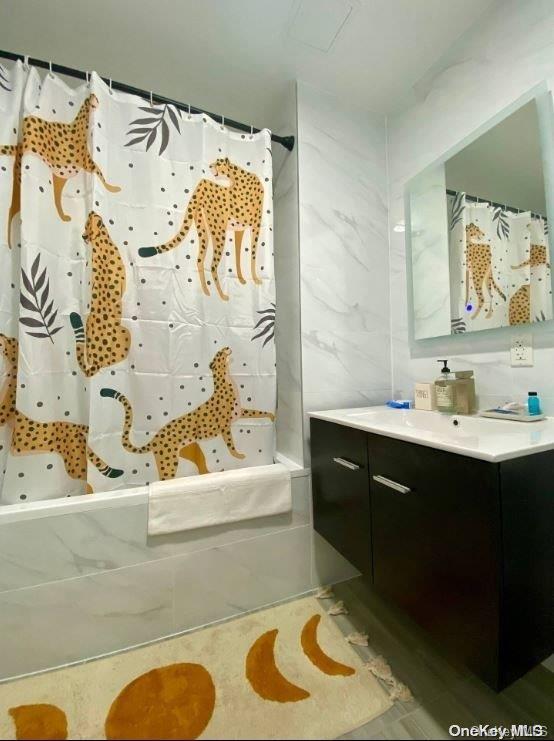 bathroom with a shower with shower curtain, vanity, and tile walls